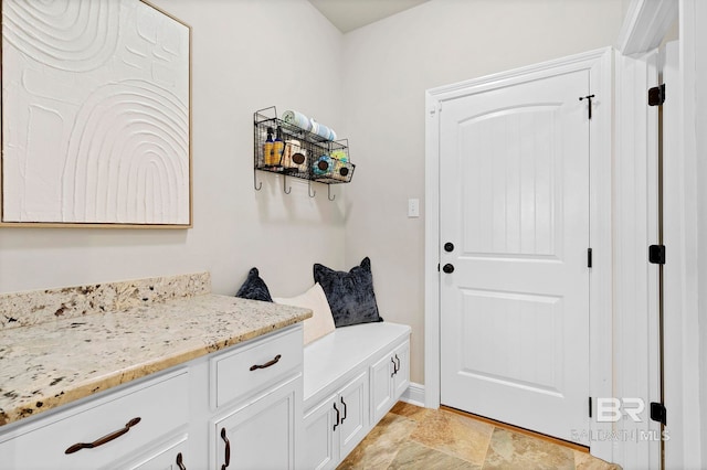 mudroom with stone finish floor and baseboards