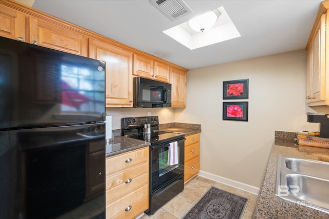 kitchen with light brown cabinets, a skylight, a sink, visible vents, and black appliances