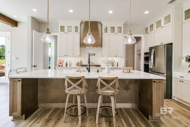 15132 Itea Dr, Foley, AL 36535 - kitchen featuring appliances with stainless steel finishes, tasteful backsplash, a large island, wood finished floors, and light countertops