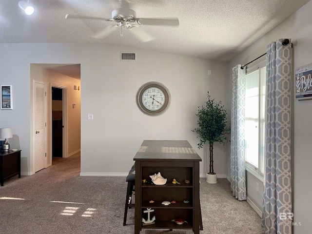 carpeted dining space with a textured ceiling and ceiling fan