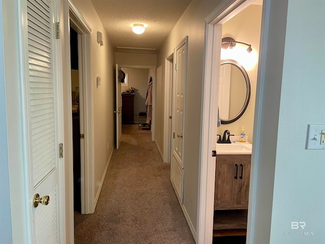 corridor featuring sink, carpet, and a textured ceiling