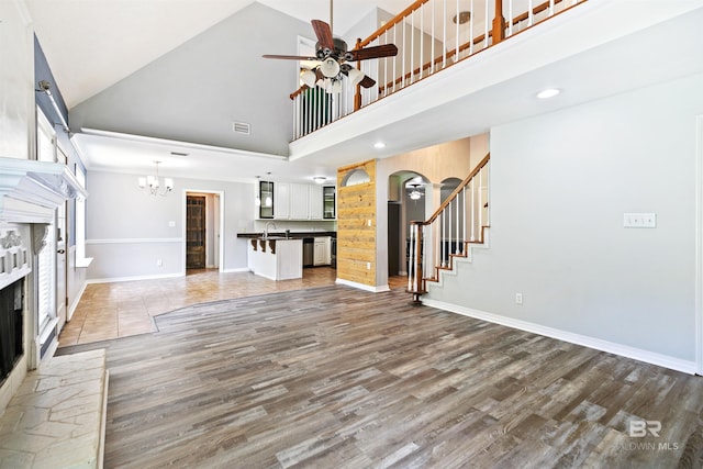 unfurnished living room featuring sink, high vaulted ceiling, hardwood / wood-style floors, and ceiling fan with notable chandelier