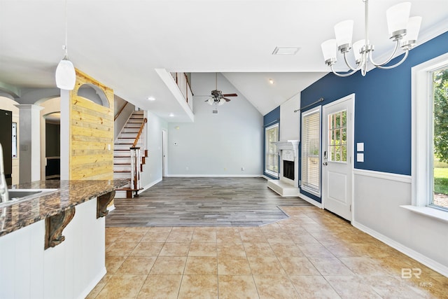 foyer entrance featuring vaulted ceiling, sink, light tile patterned flooring, and ceiling fan with notable chandelier