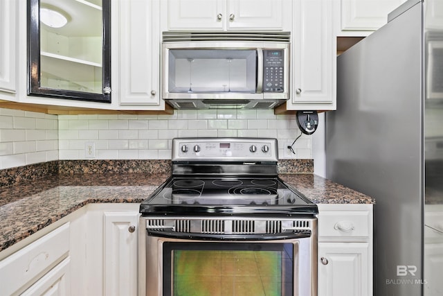 kitchen featuring dark stone countertops, white cabinetry, decorative backsplash, and appliances with stainless steel finishes