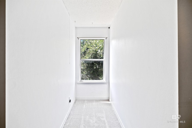 corridor featuring light carpet and a textured ceiling