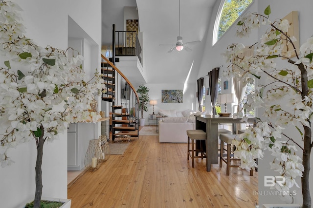 interior space featuring ceiling fan, light hardwood / wood-style floors, and a high ceiling