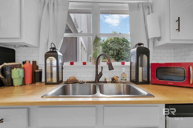 kitchen featuring white cabinets, decorative backsplash, and sink