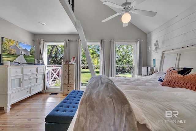 bedroom with multiple windows, light hardwood / wood-style flooring, ceiling fan, and wood walls