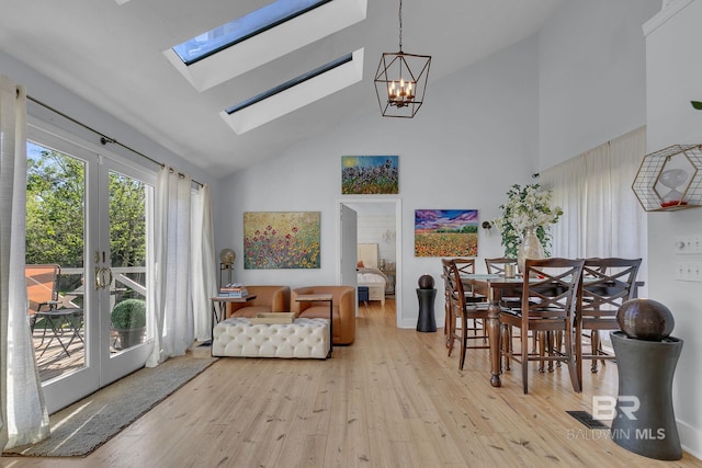 dining room featuring french doors, a skylight, high vaulted ceiling, an inviting chandelier, and light hardwood / wood-style floors