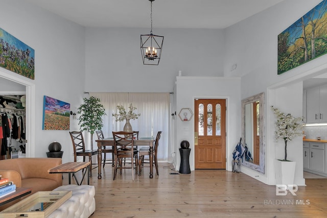 interior space with light hardwood / wood-style flooring, a high ceiling, and a notable chandelier