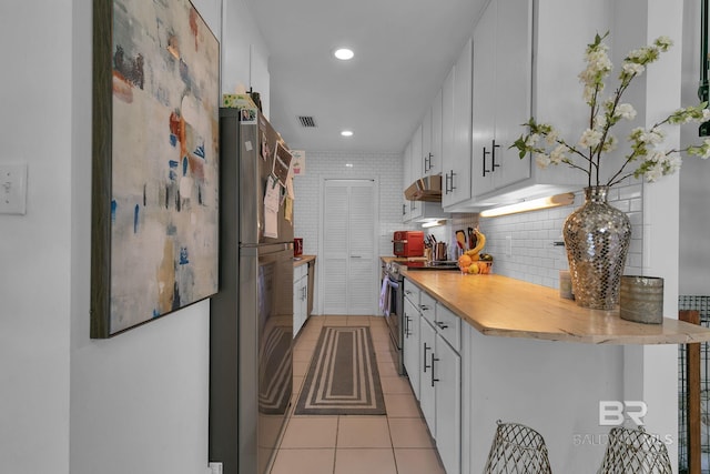 kitchen featuring white cabinets, decorative backsplash, light tile patterned flooring, and stainless steel appliances