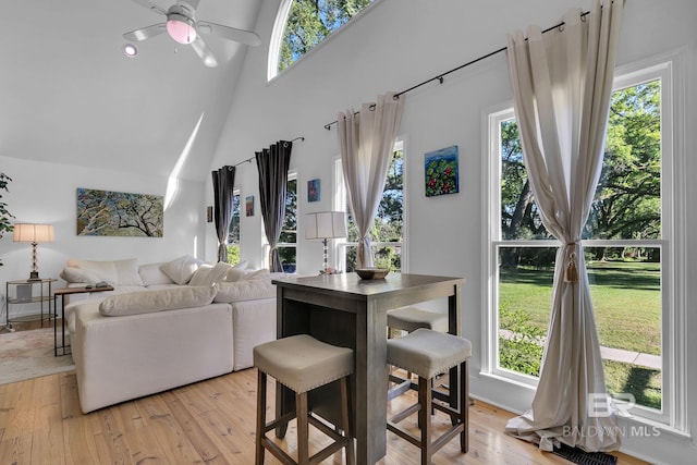 living room featuring a high ceiling, light wood-type flooring, and ceiling fan