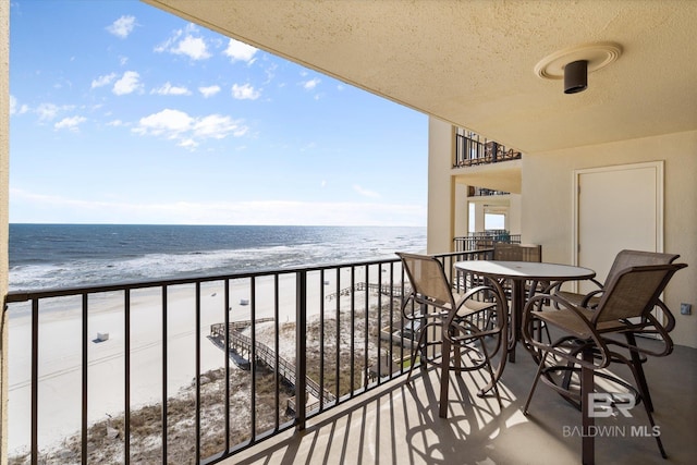 balcony with a water view and a view of the beach