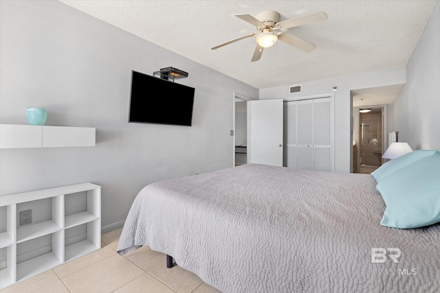 tiled bedroom with a closet, visible vents, ceiling fan, and a textured ceiling