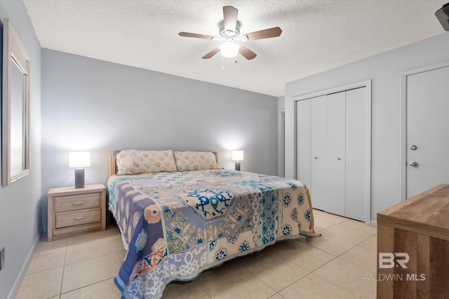 bedroom with light tile patterned floors, baseboards, a ceiling fan, a textured ceiling, and a closet