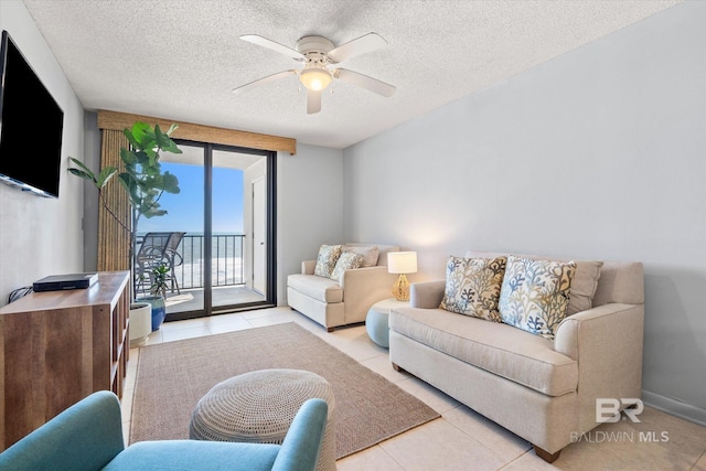 living room featuring light tile patterned floors, a textured ceiling, a ceiling fan, and baseboards