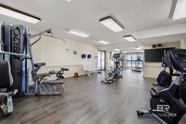 gym with a textured ceiling and wood finished floors