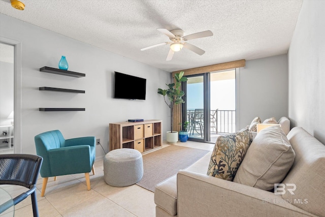 living area featuring ceiling fan, a textured ceiling, and tile patterned flooring