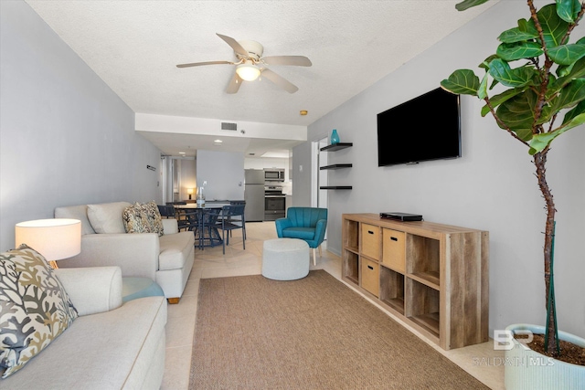 living room with ceiling fan, light tile patterned floors, a textured ceiling, and visible vents