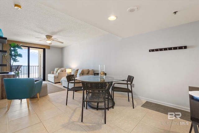 dining room with light tile patterned floors, ceiling fan, baseboards, and a textured ceiling