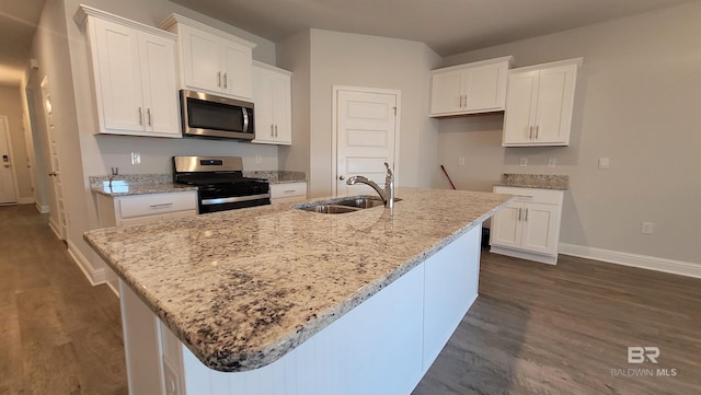 kitchen with white cabinetry, sink, stainless steel appliances, and a center island with sink