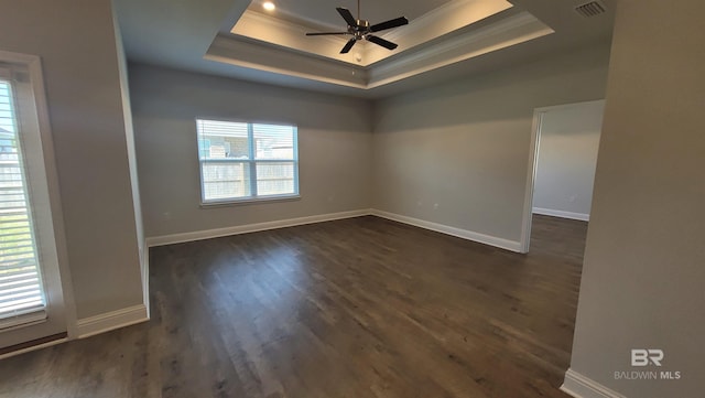 empty room with a tray ceiling, ornamental molding, dark hardwood / wood-style floors, and ceiling fan