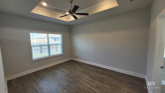 spare room featuring crown molding, a tray ceiling, dark wood-type flooring, and ceiling fan