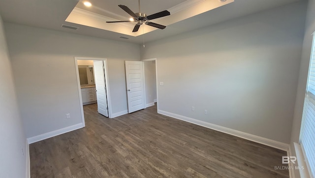 unfurnished bedroom featuring ensuite bath, ornamental molding, dark hardwood / wood-style floors, a raised ceiling, and ceiling fan