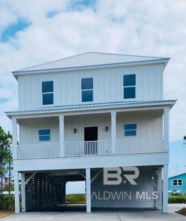 beach home featuring a carport, concrete driveway, board and batten siding, and metal roof