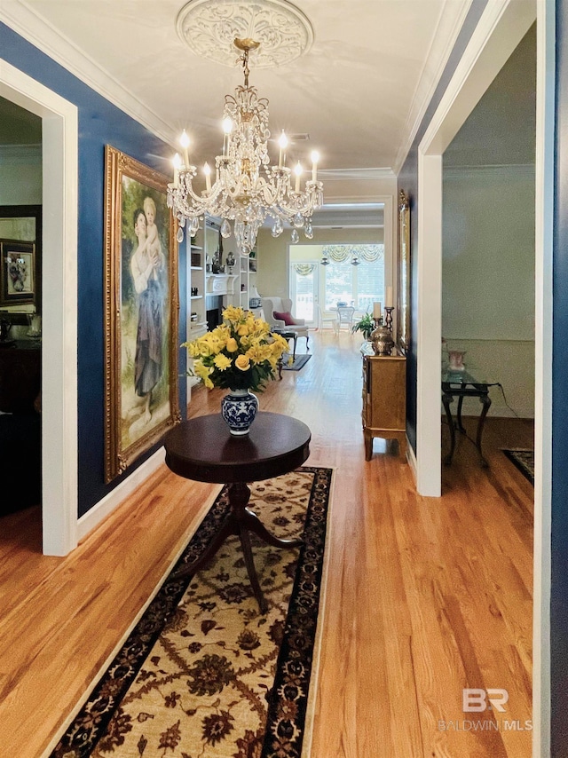 hall with a notable chandelier, wood-type flooring, and crown molding