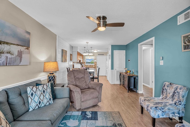 728 W Beach Blvd Unit 121, Gulf Shores, AL 36542 - living room with light wood-type flooring, visible vents, ceiling fan with notable chandelier, and a textured ceiling