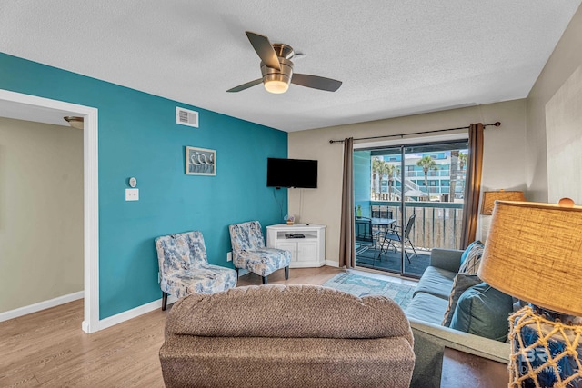 728 W Beach Blvd Unit 121, Gulf Shores, AL 36542 - living room featuring wood finished floors, a textured ceiling, visible vents, ceiling fan, and baseboards