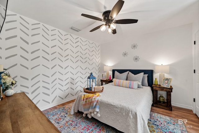 bedroom featuring baseboards, ceiling fan, wood finished floors, and visible vents