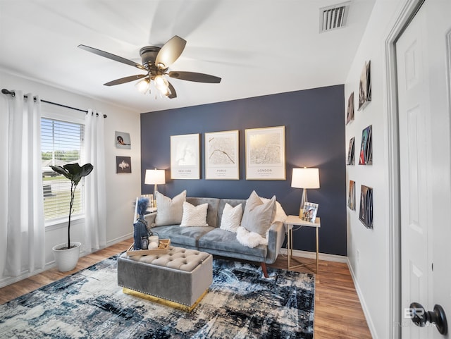 living area featuring a ceiling fan, baseboards, visible vents, and wood finished floors