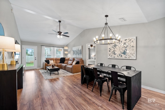 dining space with visible vents, wood finished floors, baseboards, ceiling fan with notable chandelier, and lofted ceiling