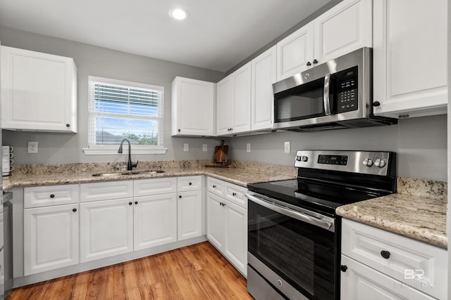kitchen featuring a sink, white cabinets, light wood-style floors, stainless steel appliances, and recessed lighting