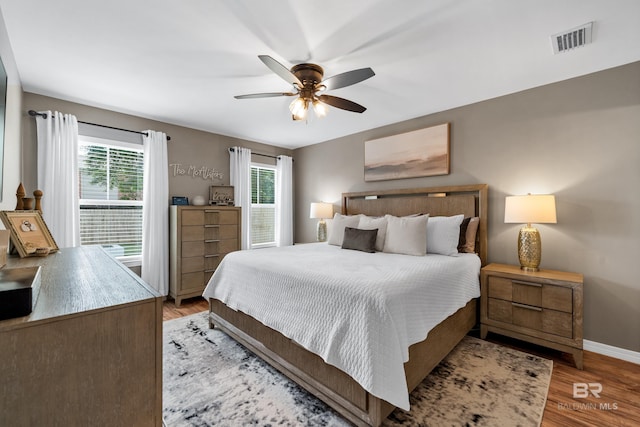 bedroom with visible vents, baseboards, ceiling fan, and wood finished floors