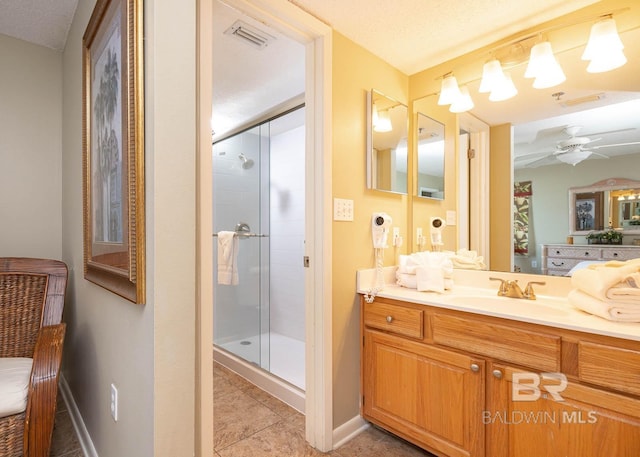 bathroom featuring vanity, a shower with door, tile patterned flooring, ceiling fan, and a textured ceiling