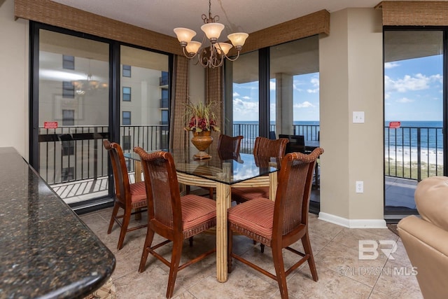 tiled dining room featuring a beach view, a water view, and an inviting chandelier