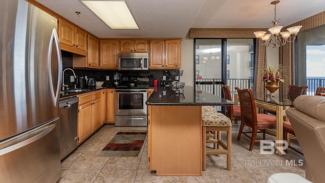 kitchen with a breakfast bar, sink, decorative light fixtures, a kitchen island, and stainless steel appliances