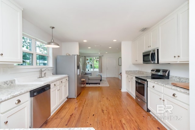 kitchen with sink, appliances with stainless steel finishes, a healthy amount of sunlight, and light hardwood / wood-style floors