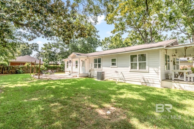 back of property with a lawn, a patio area, and central air condition unit