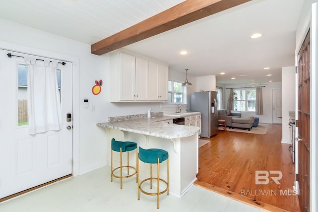 kitchen with white cabinetry, hanging light fixtures, beam ceiling, stainless steel appliances, and kitchen peninsula