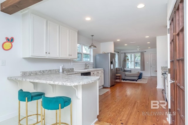 kitchen with stainless steel refrigerator with ice dispenser, a kitchen breakfast bar, kitchen peninsula, pendant lighting, and white cabinets