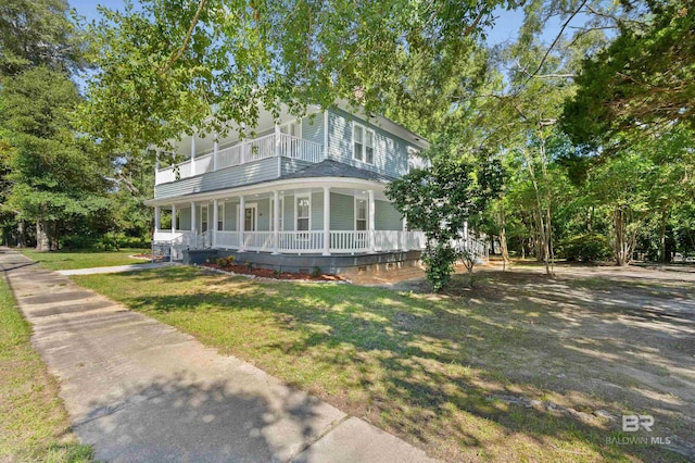 country-style home with a balcony, a front yard, and a porch