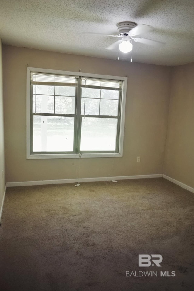 carpeted empty room featuring ceiling fan and a textured ceiling