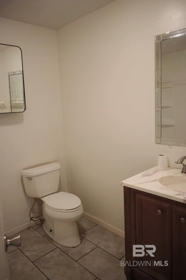 bathroom with tile flooring, toilet, and vanity