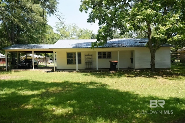 rear view of house featuring a carport and a yard