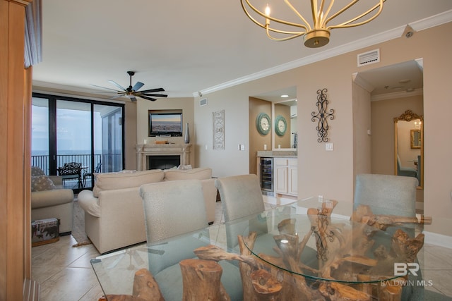 tiled dining area with ceiling fan with notable chandelier, beverage cooler, and crown molding