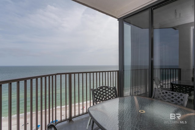 balcony featuring a view of the beach and a water view